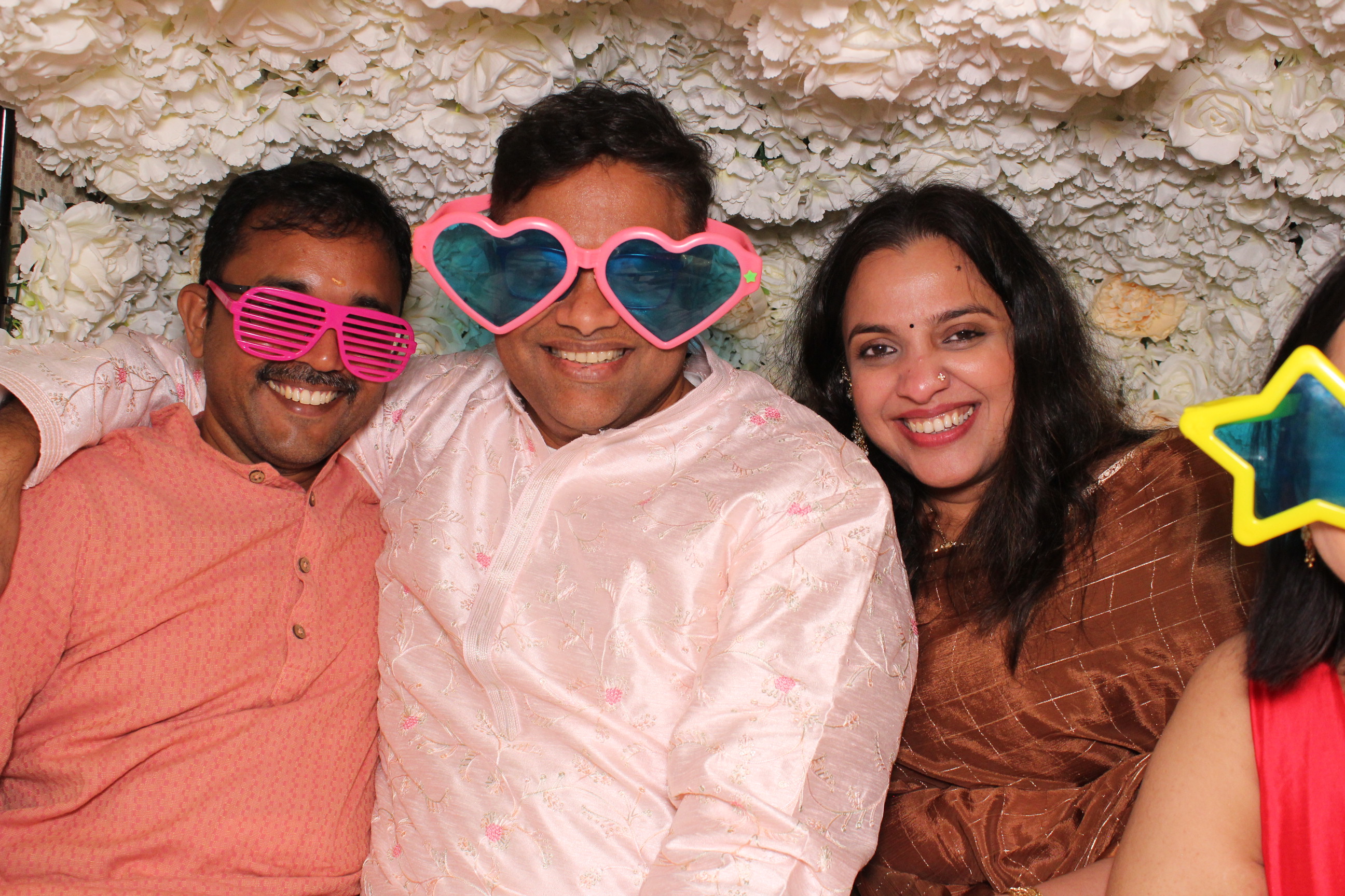 Wedding guests wearing silly hats in a colourful tuk tuk photobooth experience